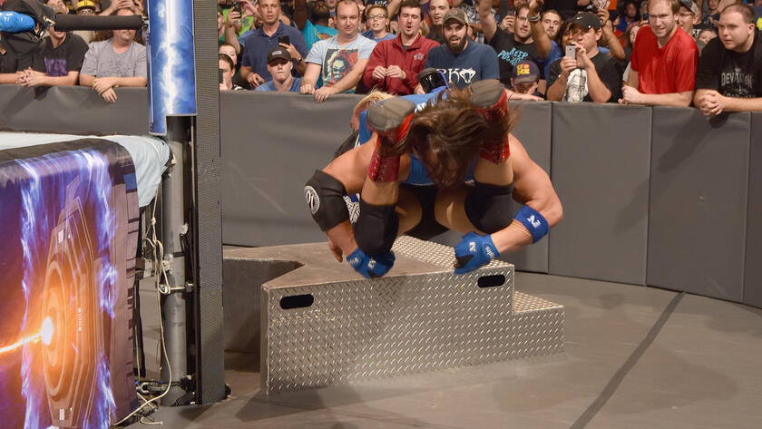 He hits the underdog with a vicious Styles Clash on the steel steps.