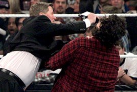 John Laurinaitis hits Mick Foley with a microphone