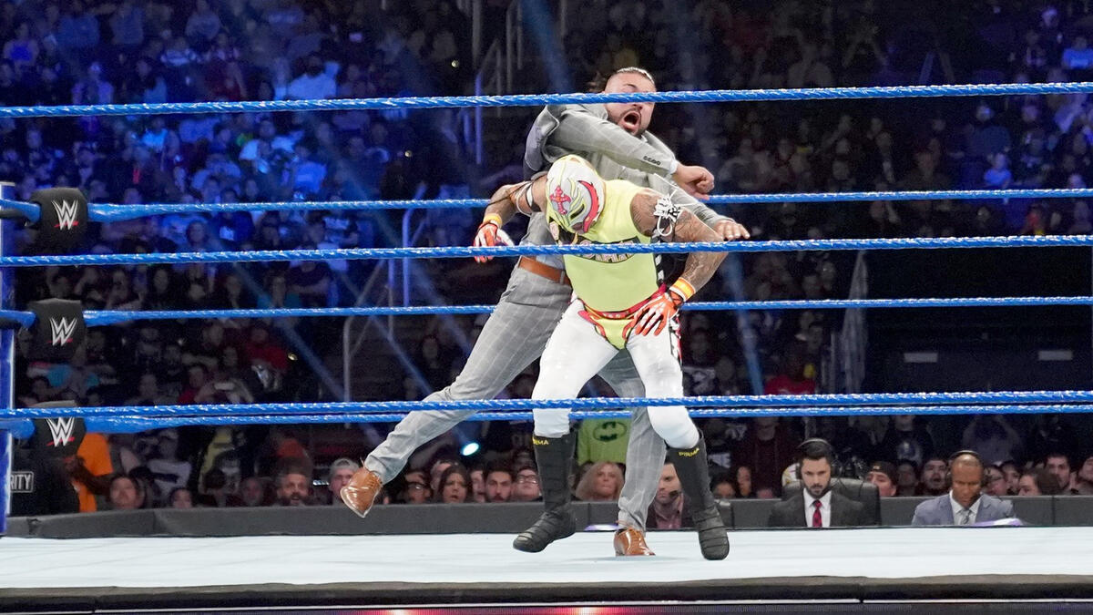 Suddenly, Andrade attacks Mysterio from behind!