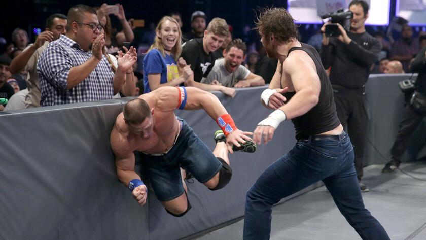 The Triple Threat Match spills outside the ring early as The Lunatic Fringe tosses Cena into a barrier.