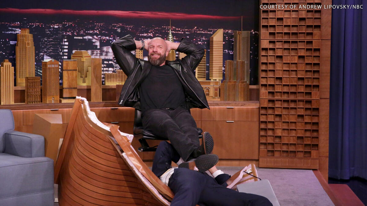 Triple H rests his legs on Tonight Show host Jimmy Fallon after slamming him through in 2017. [Photo: Andrew Lipovsky/NBC]